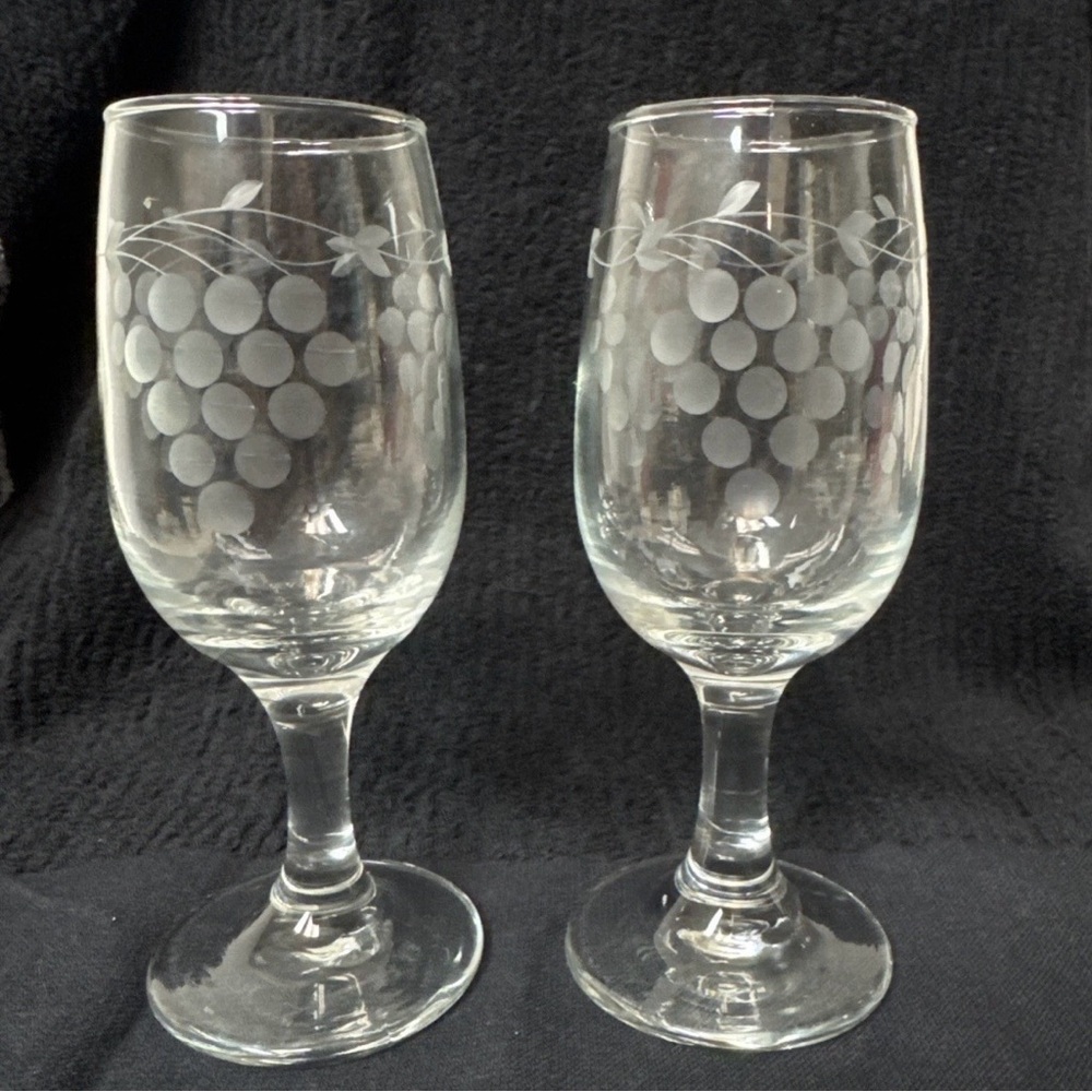 Two VTG stemmed wine glasses with an acid-etched grape cluster/vine motif.